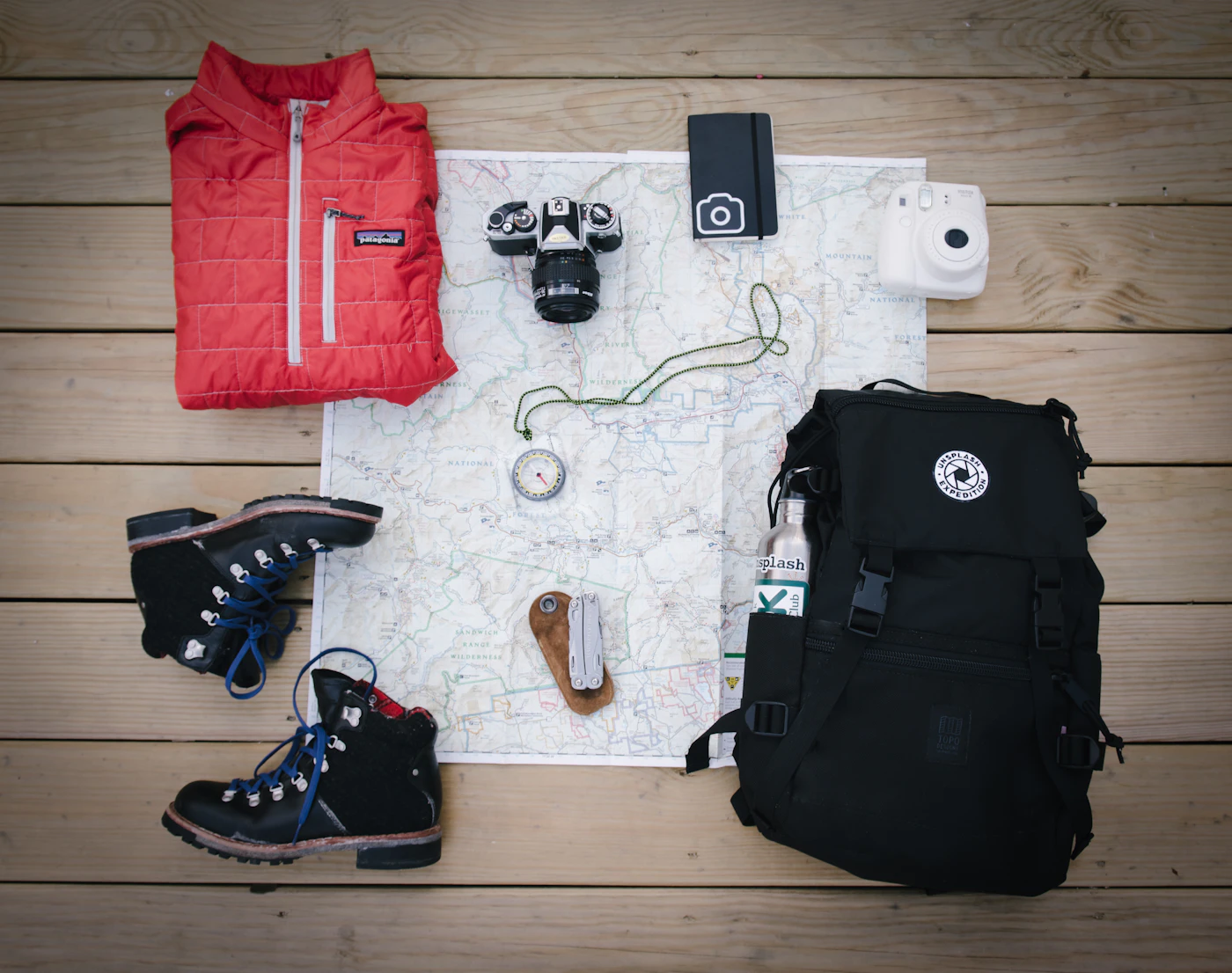 Hiking backpack, boots, jacket and map laid out before a trip