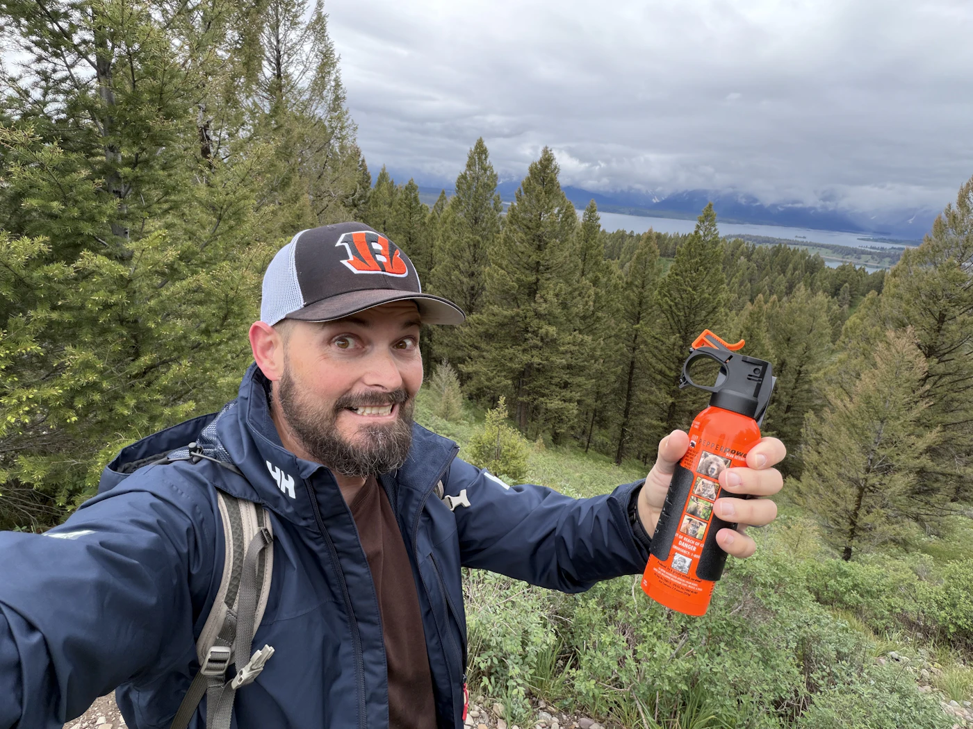 Hiker holding a can of bear spray on a forested mountain trail